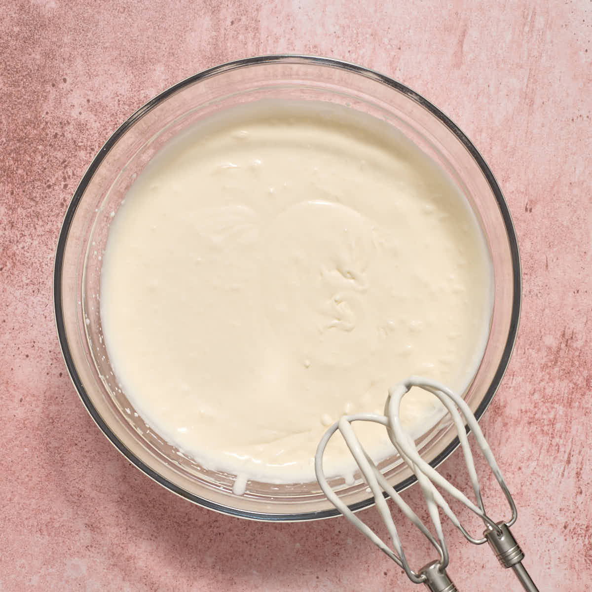 Partially whipped frosting in a glass bowl.