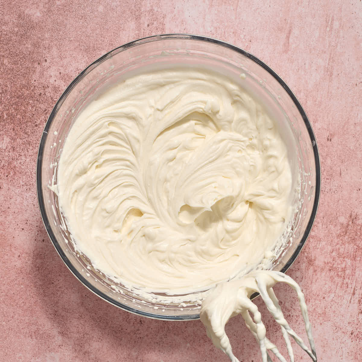 Fully whipped frosting in a glass bowl.