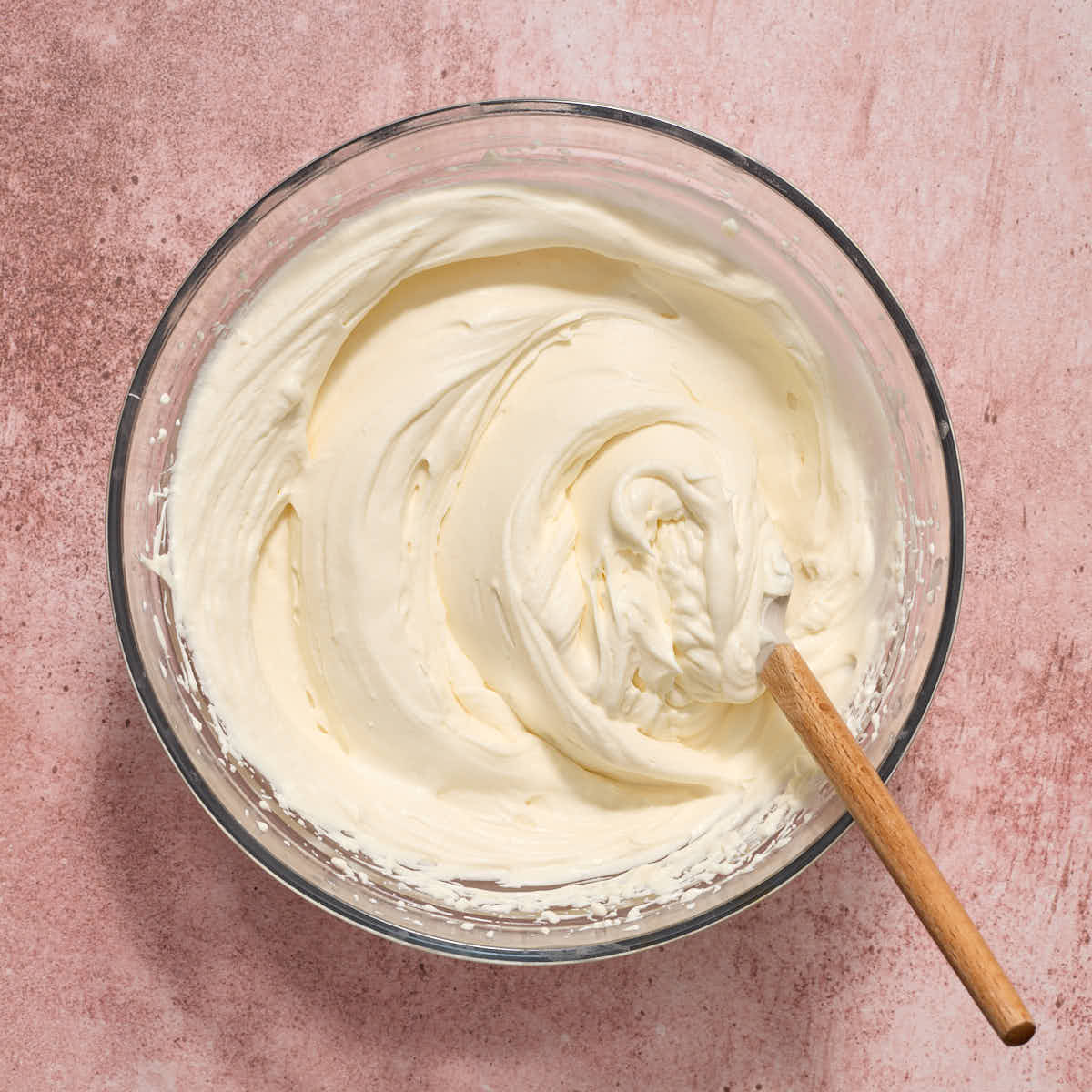 Frosting in a bowl with a spatula inserted into it.