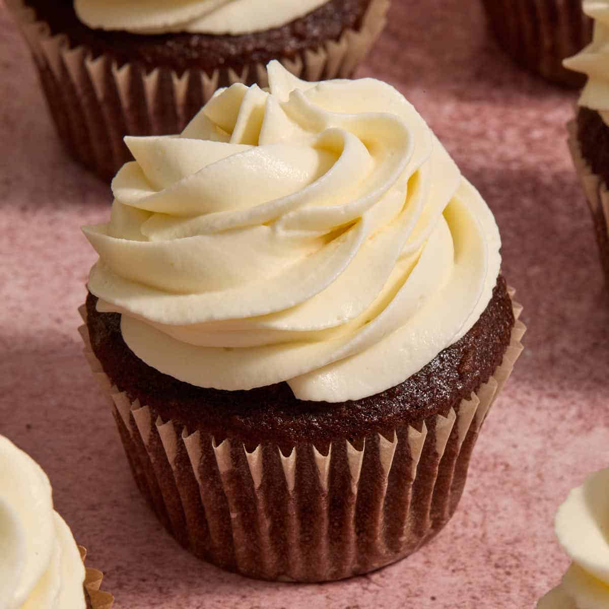 Whipped cream cheese frosting piped on top of a chocolate cupcake.