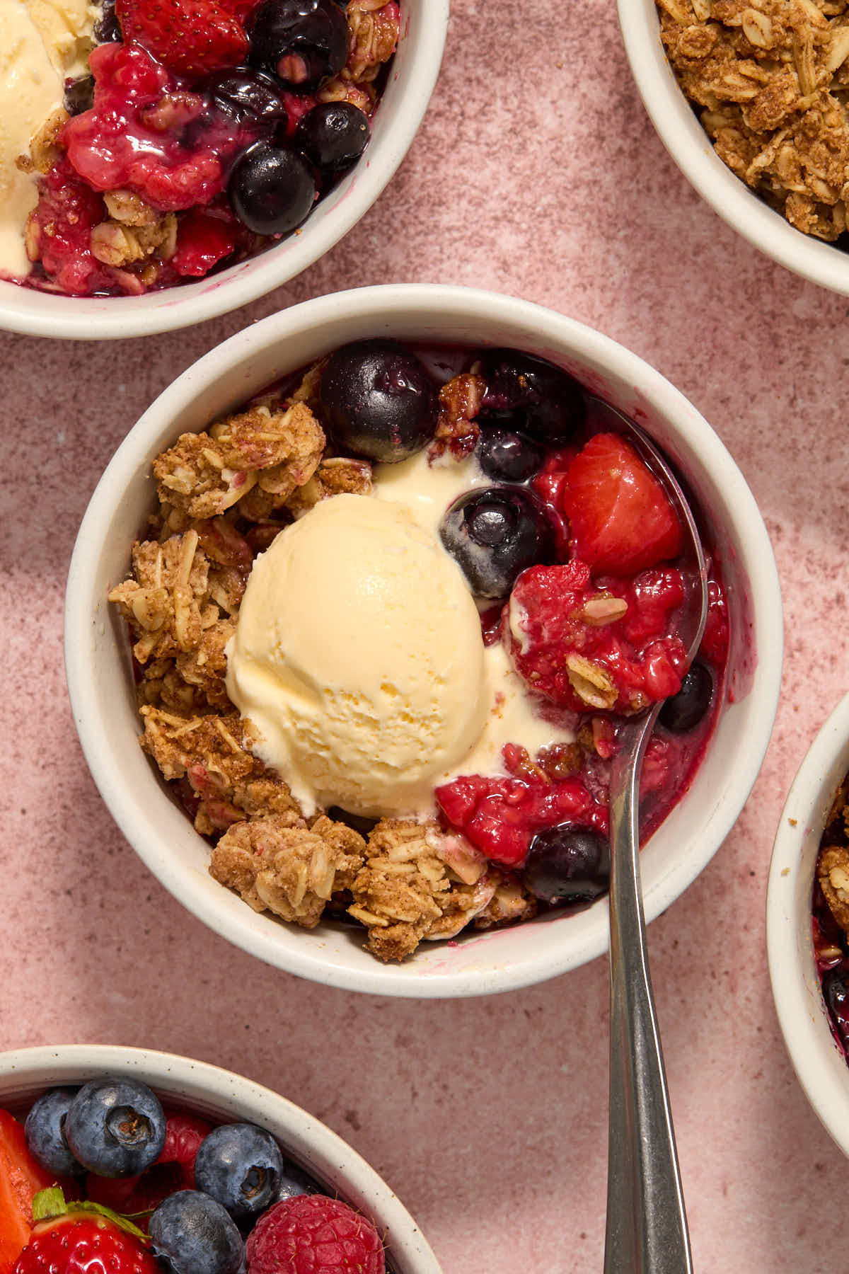 Individual berry crisps in ramekins with ice cream on top.