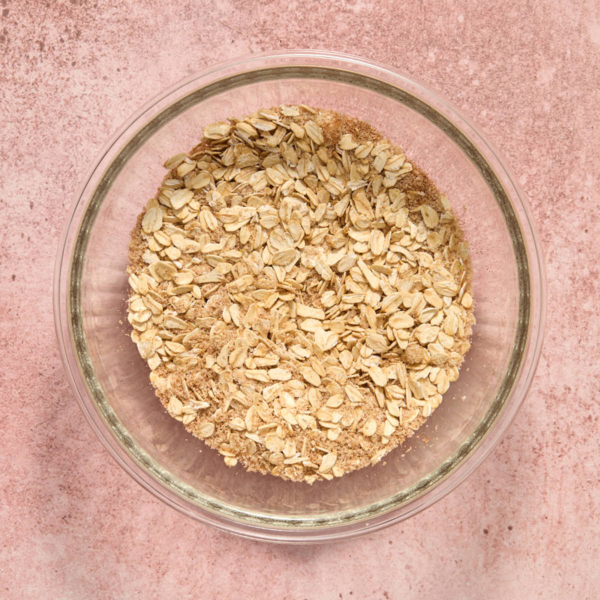 Dry oat mixture combined in a glass bowl.
