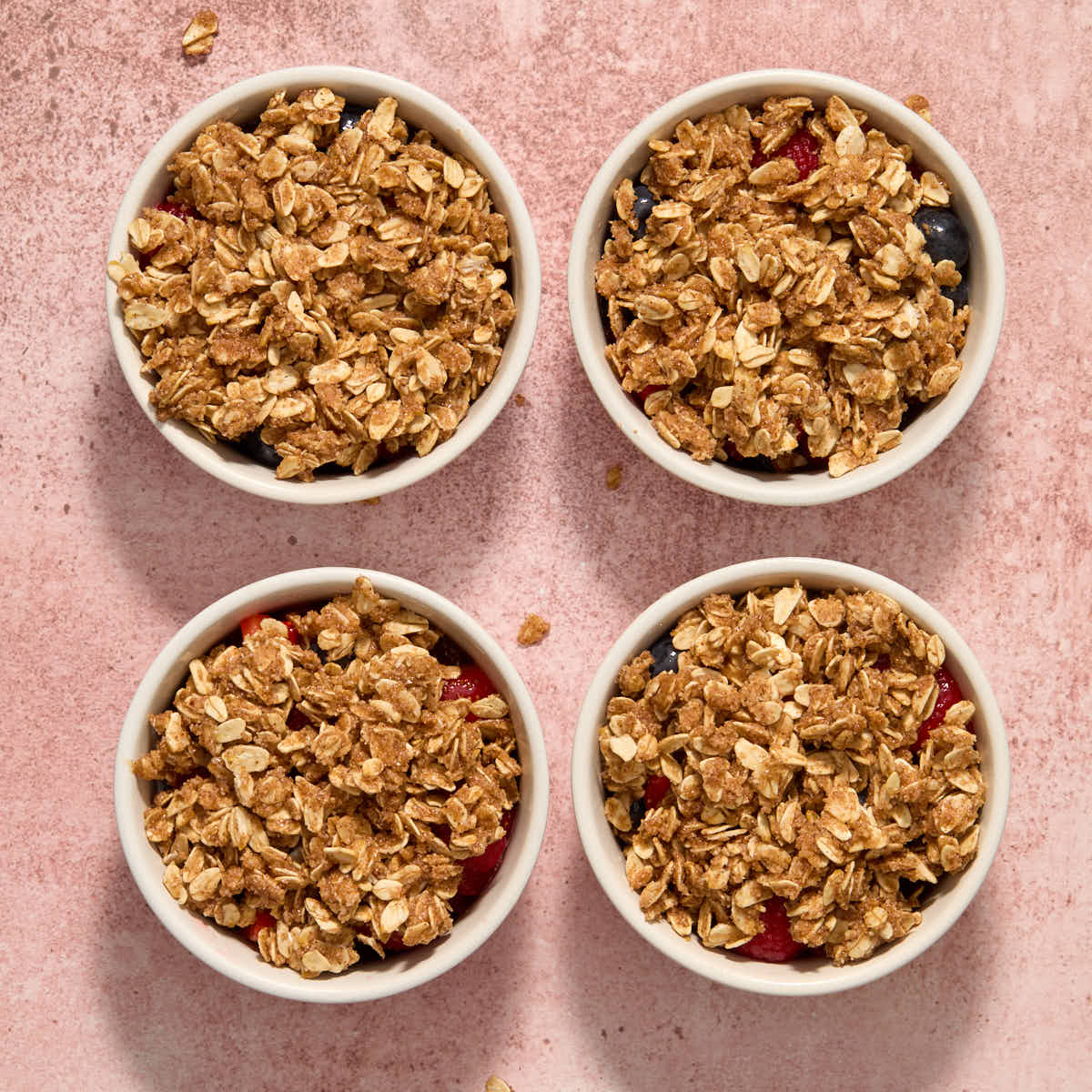 Crisp topping added on top of the berries in each ramekin.
