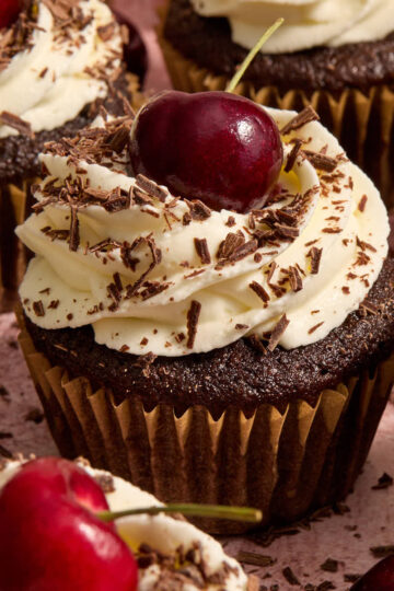 Almond flour black forest cupcakes topped with fresh cherries and chocolate shavings.