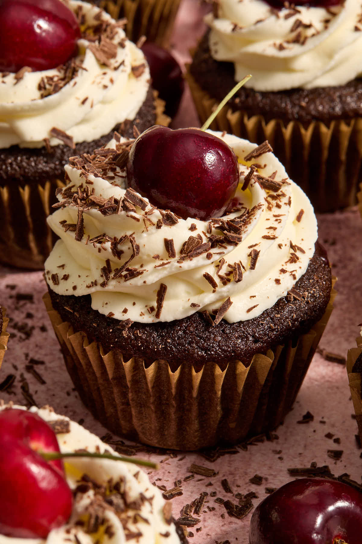 Close up of a cupcake topped with a fresh cherry.