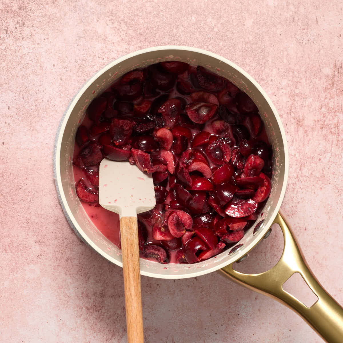 Cherry filling ingredients in a small saucepan with a spatula inserted into it.