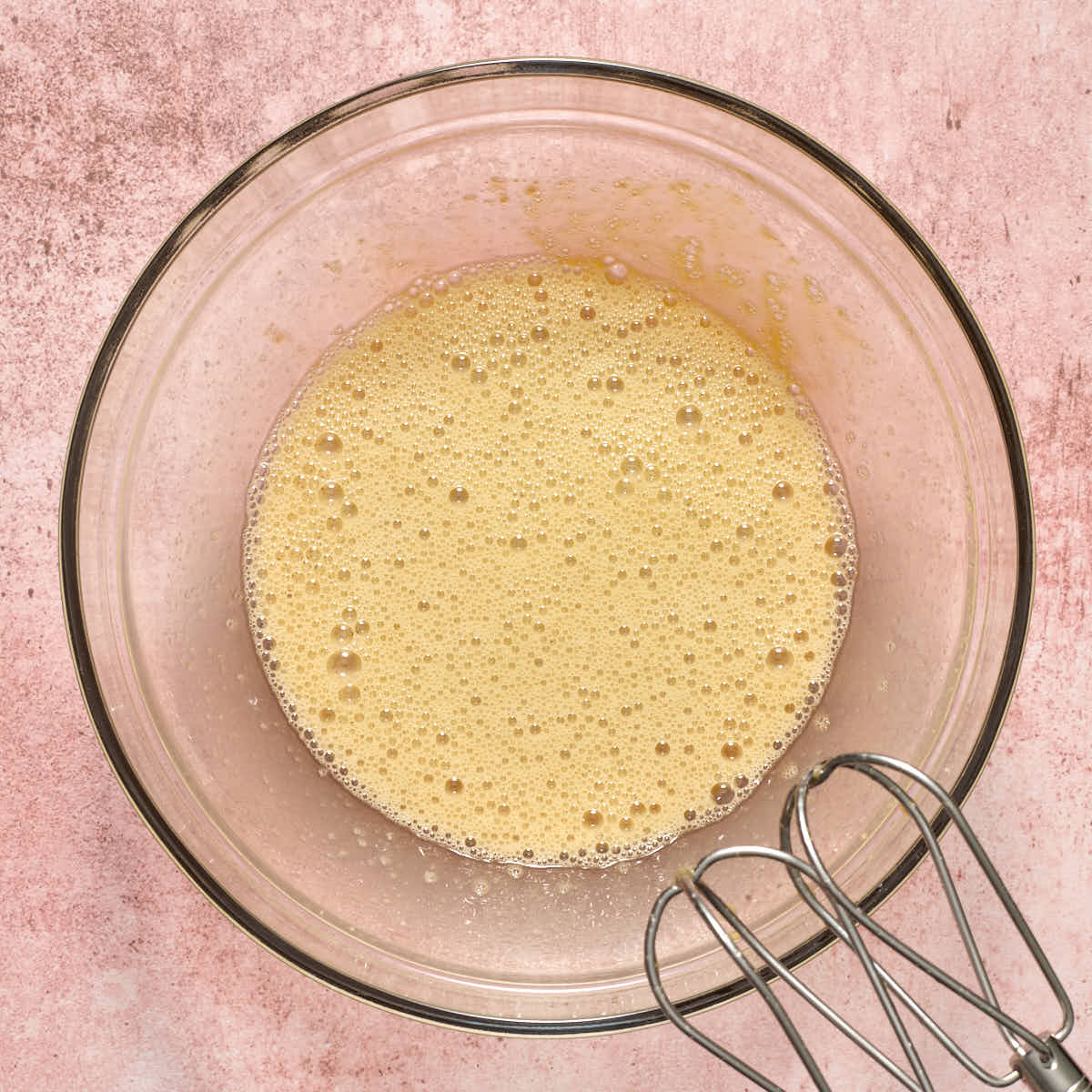 Brown sugar and eggs whipped together in a glass bowl.