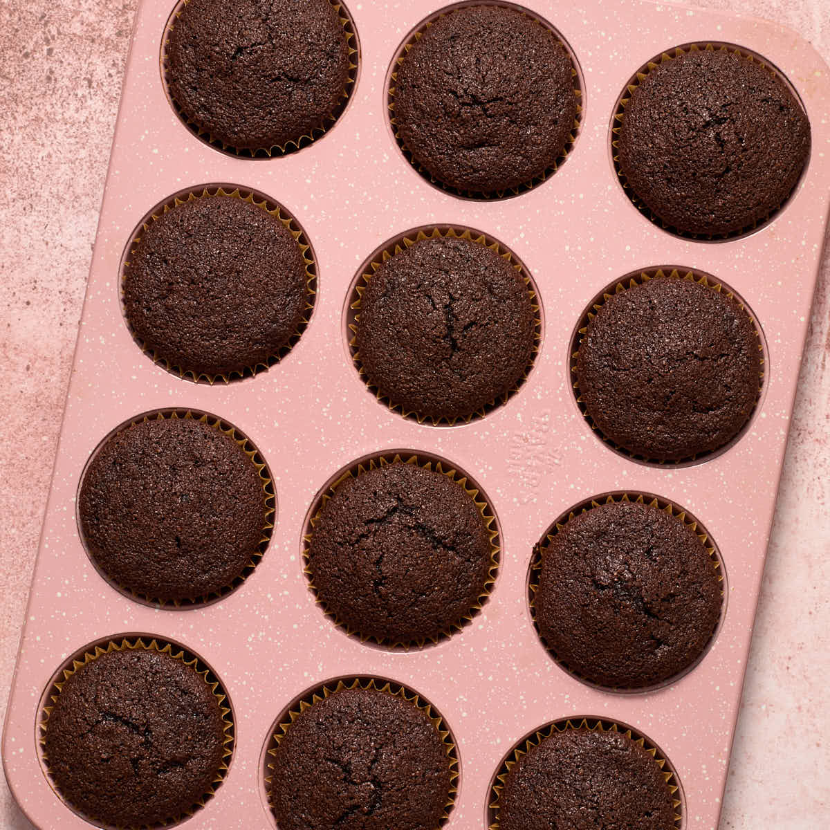 Baked chocolate cupcakes in a pink cupcake pan.