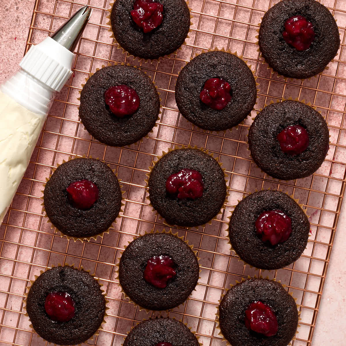Cherry filling piped into cupcake centers.