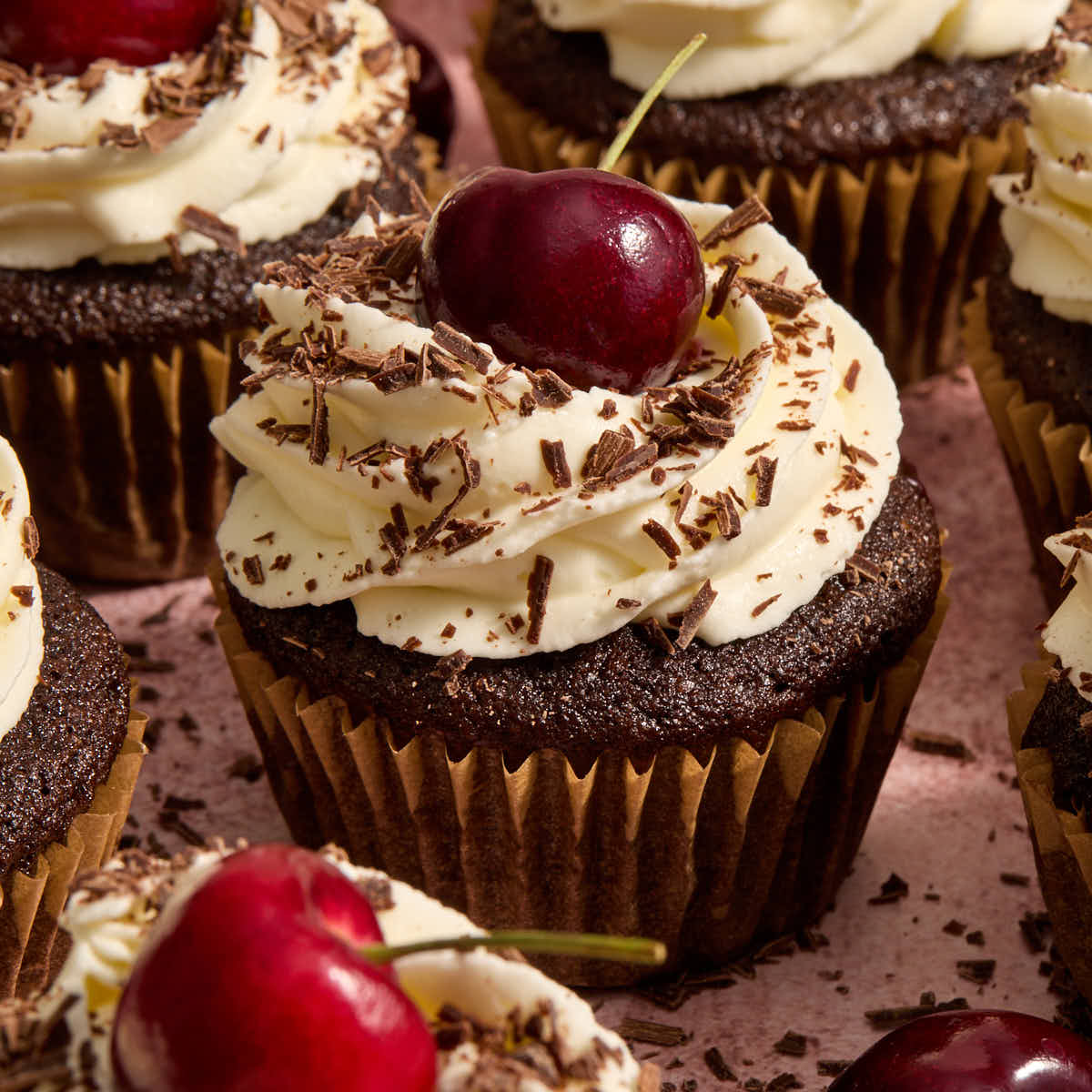 Almond flour black forest cupcakes topped with fresh cherries and chocolate shavings.