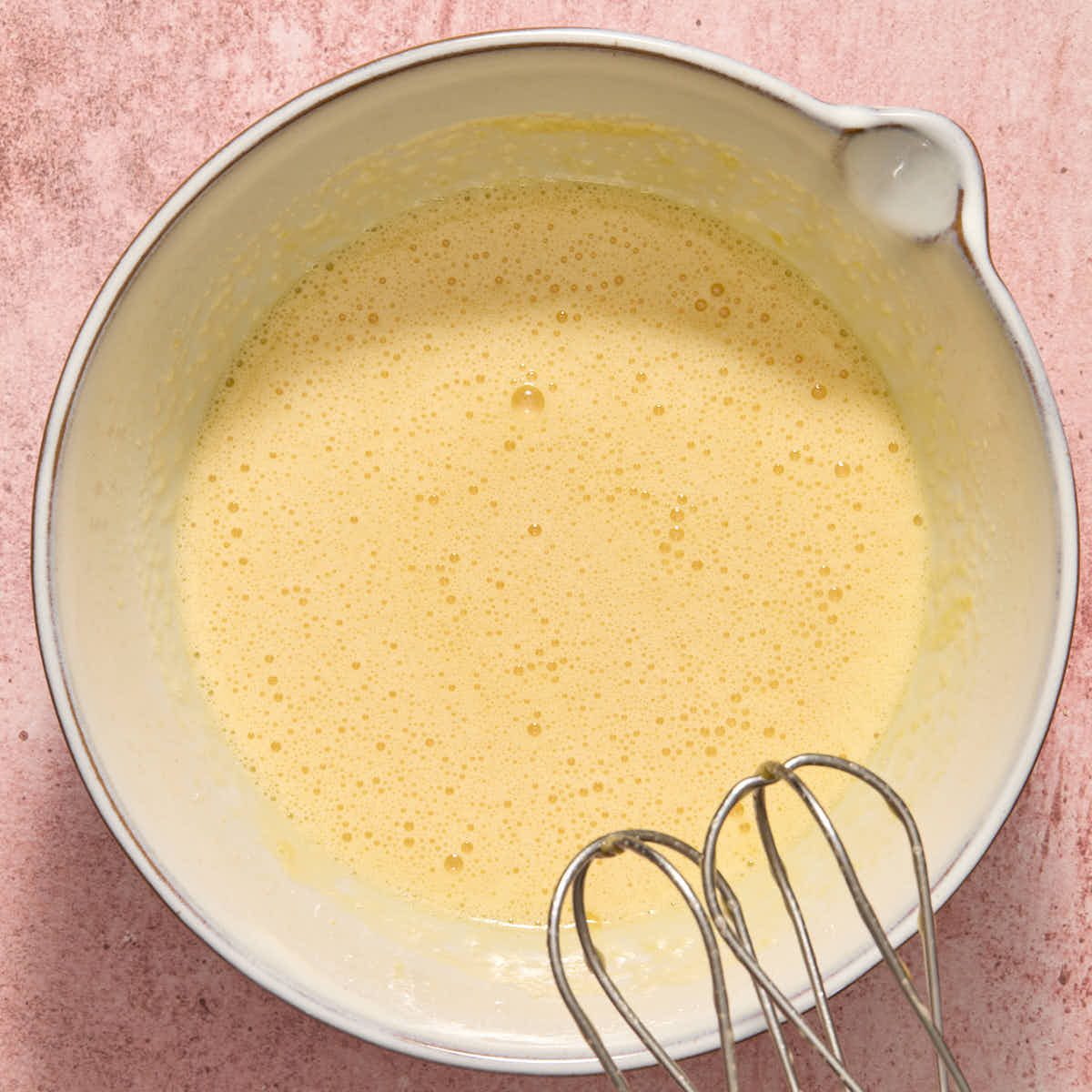 Oil and vanilla mixed into egg mixture in a white bowl.