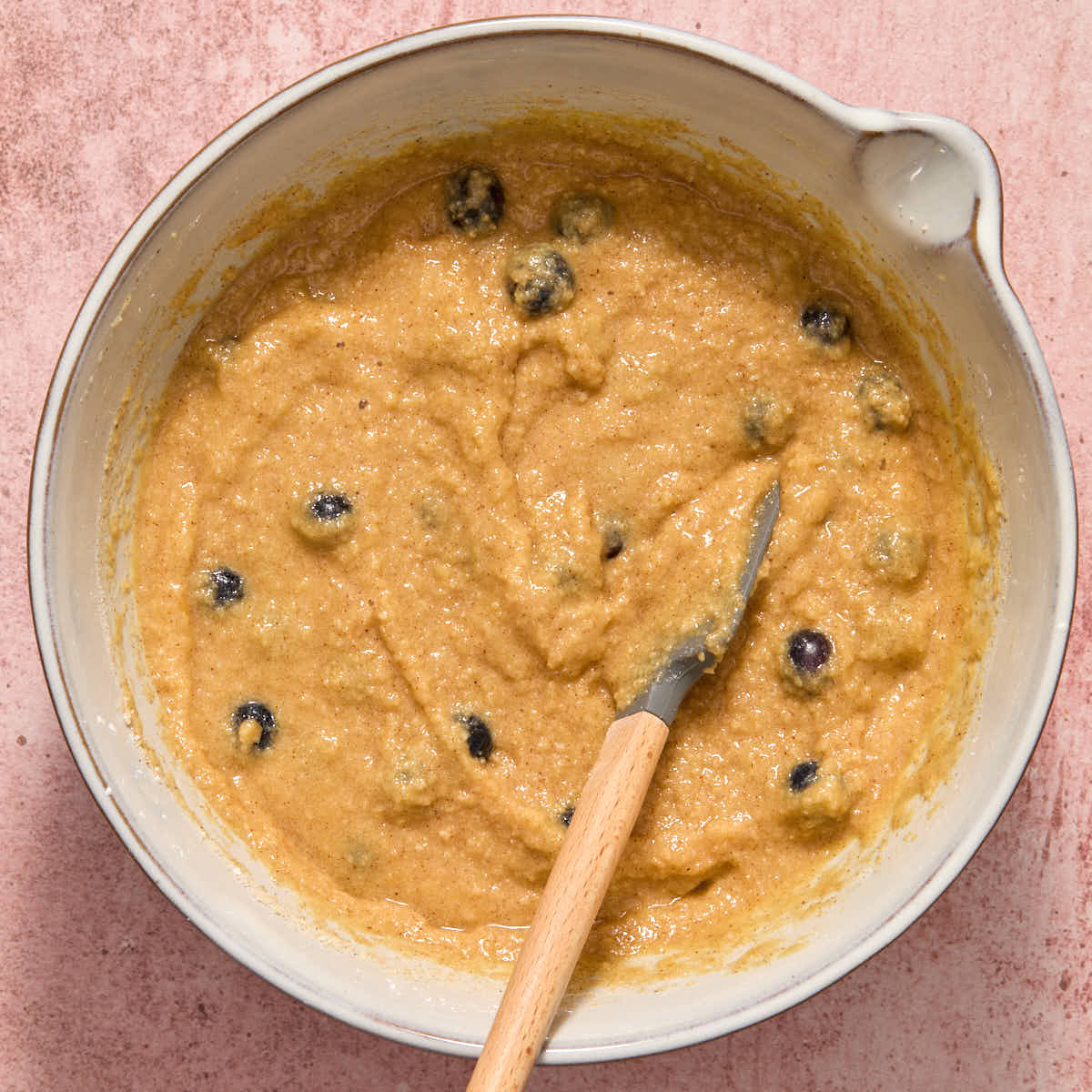 Blueberries folded into the batter with a spatula.