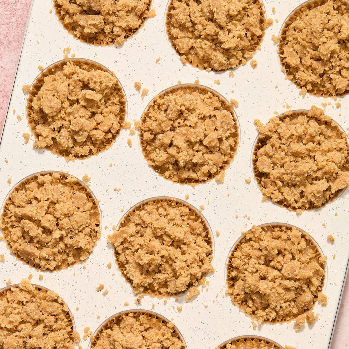 Batter in muffin pan with streusel topping added to each muffin.