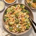 Broccoli caesar pasta salad in a large bowl with serving spoons.