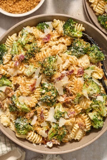 Broccoli caesar pasta salad in a large bowl with serving spoons.
