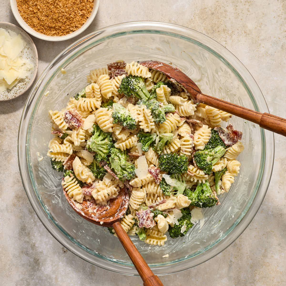 Salad ingredients being tossed together in a large glass bowl.