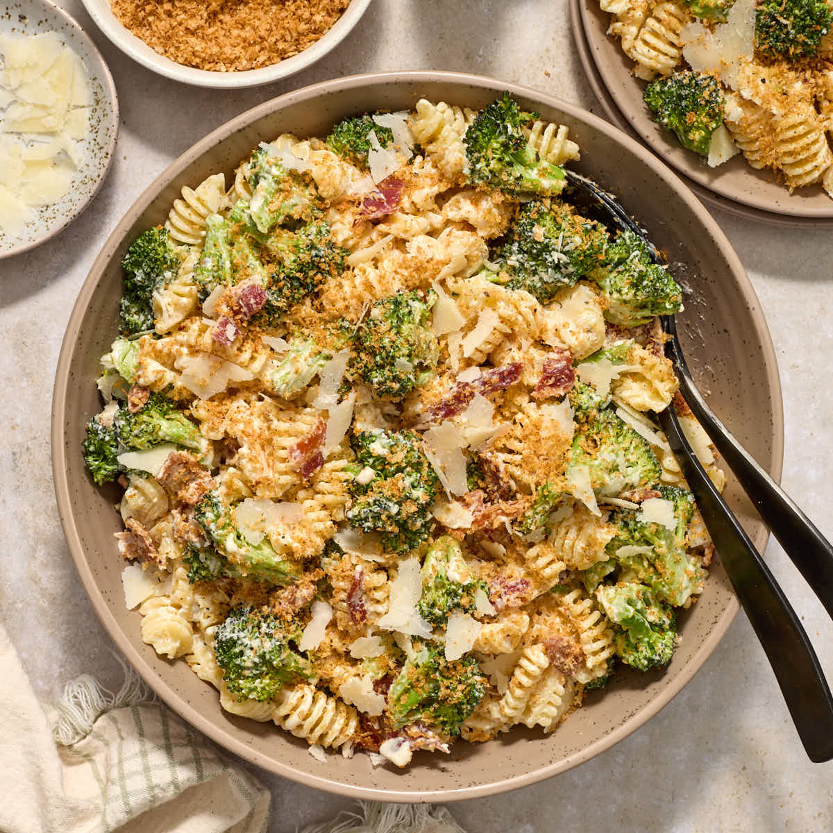Broccoli caesar pasta salad in a large bowl with serving spoons.