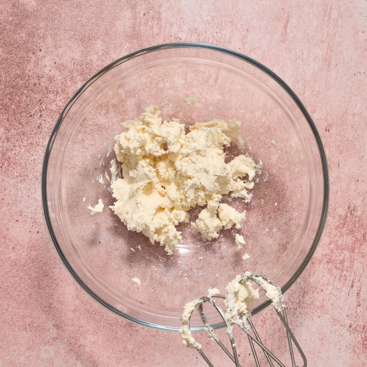 Vanilla and cream cheese beaten together in a glass bowl.