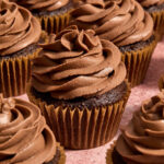 Chocolate cupcakes with chocolate whipped cream cheese frosting piped on top.