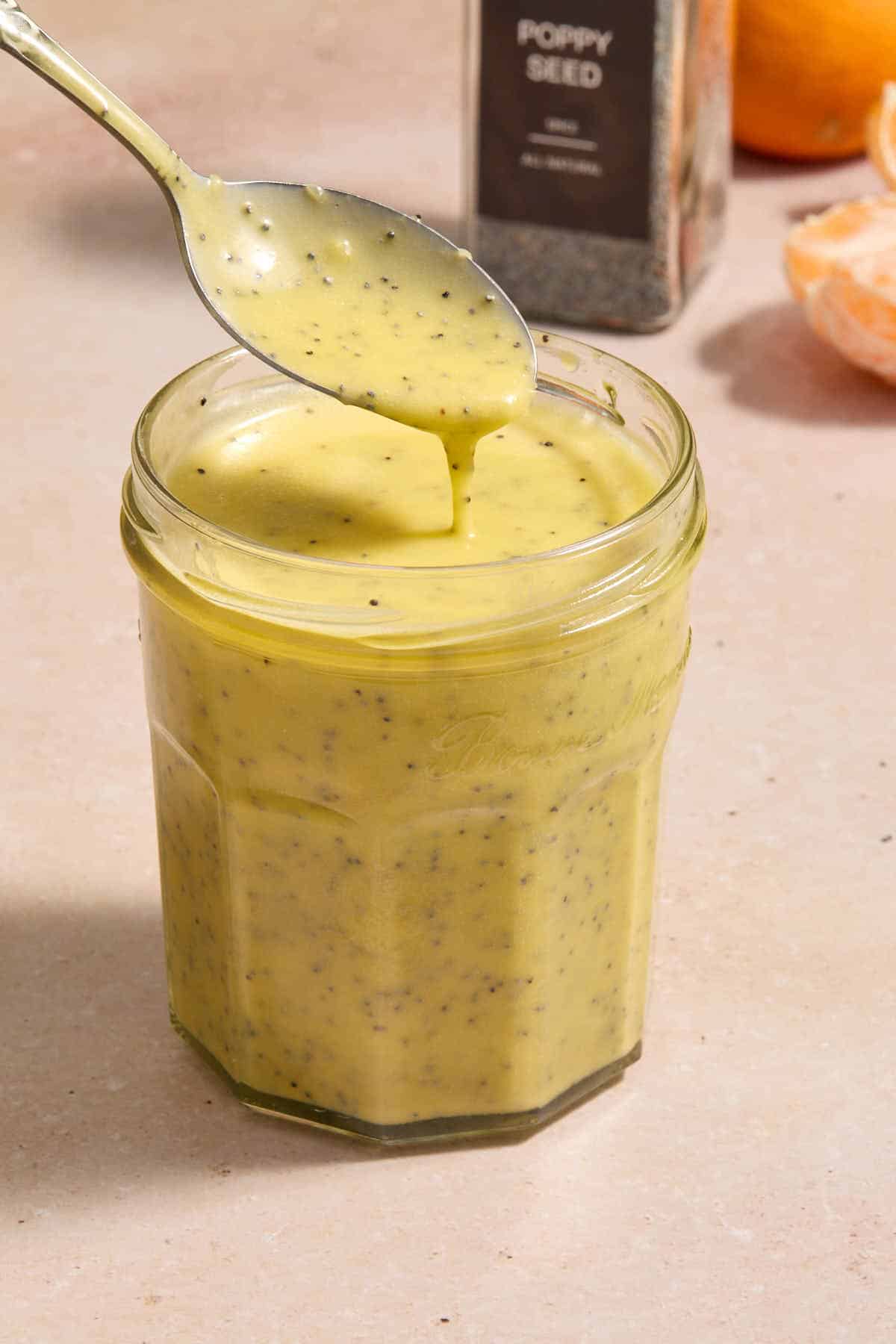 Dressing in a glass jar with a spoon lifting some out.