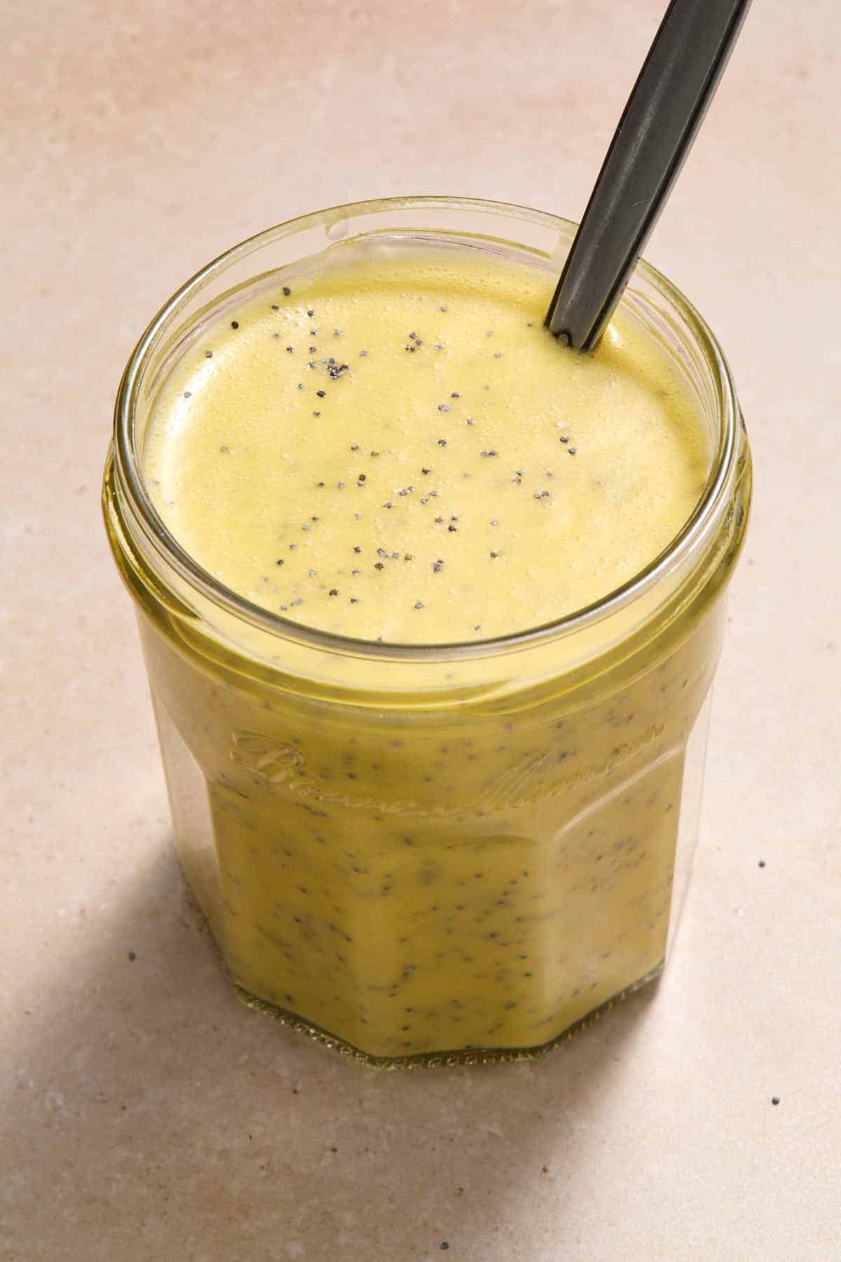 Dressing in a glass jar with a spoon inserted into it.
