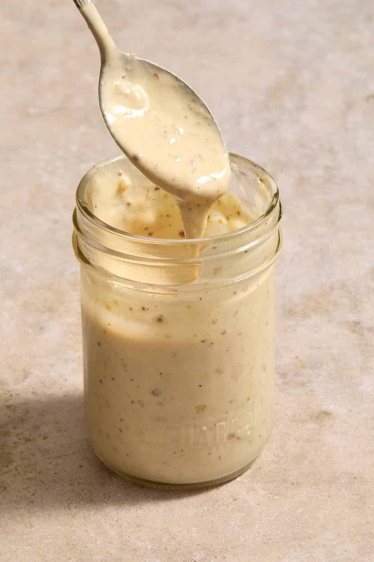 Dressing in a jar with a spoonful being lifted out.