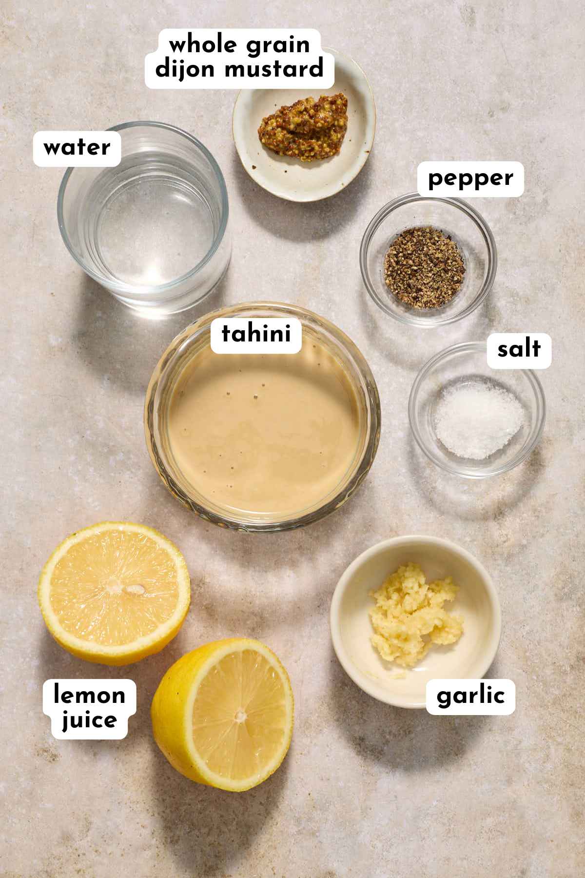 Ingredients to make tahini caesar salad dressing arranged individually and labeled.