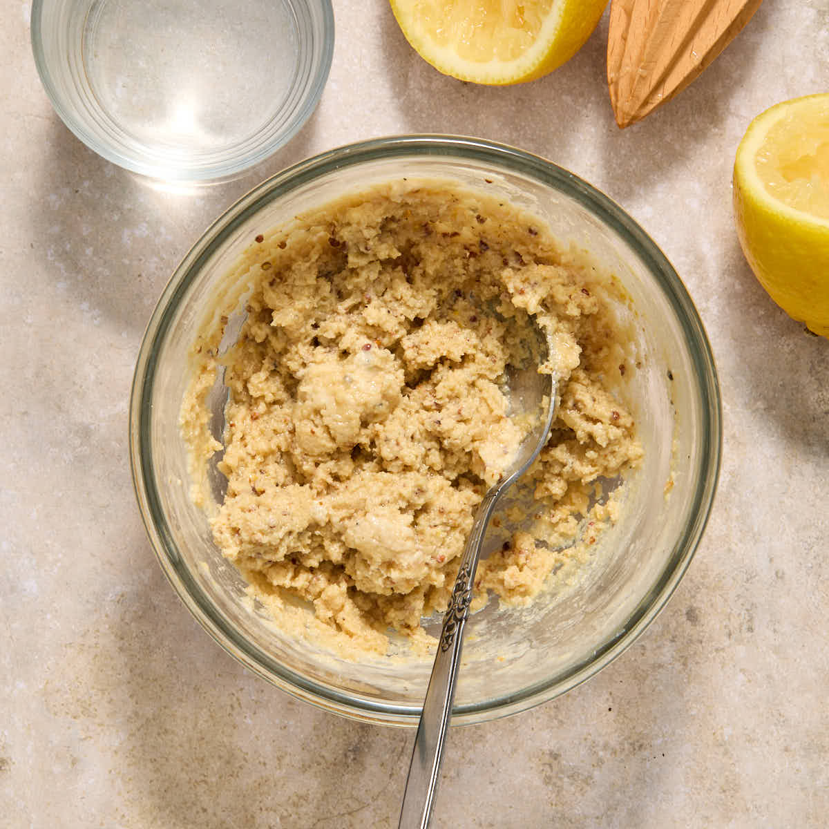 Ingredients, except water, mixed together in a glass bowl to create a thick paste.