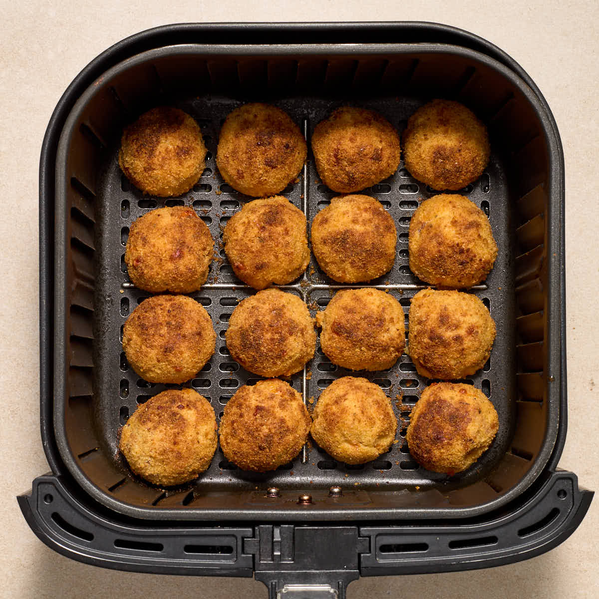 Air fried potato balls in an air fryer basket.