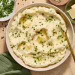Air fryer mashed potatoes served in a bowl with chopped chives, butter and pepper on top.
