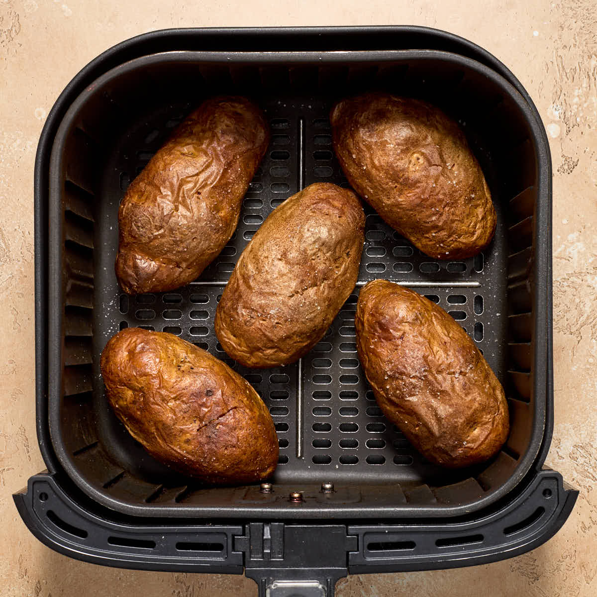 Baked potatoes in an air fryer basket.