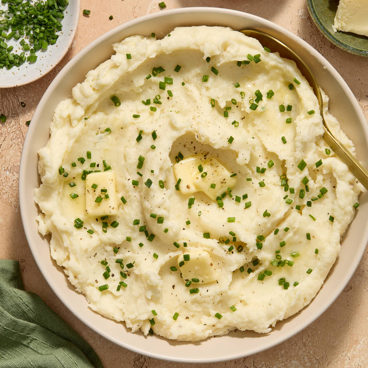 Mashed potatoes served in a bowl with fresh chives and butter.
