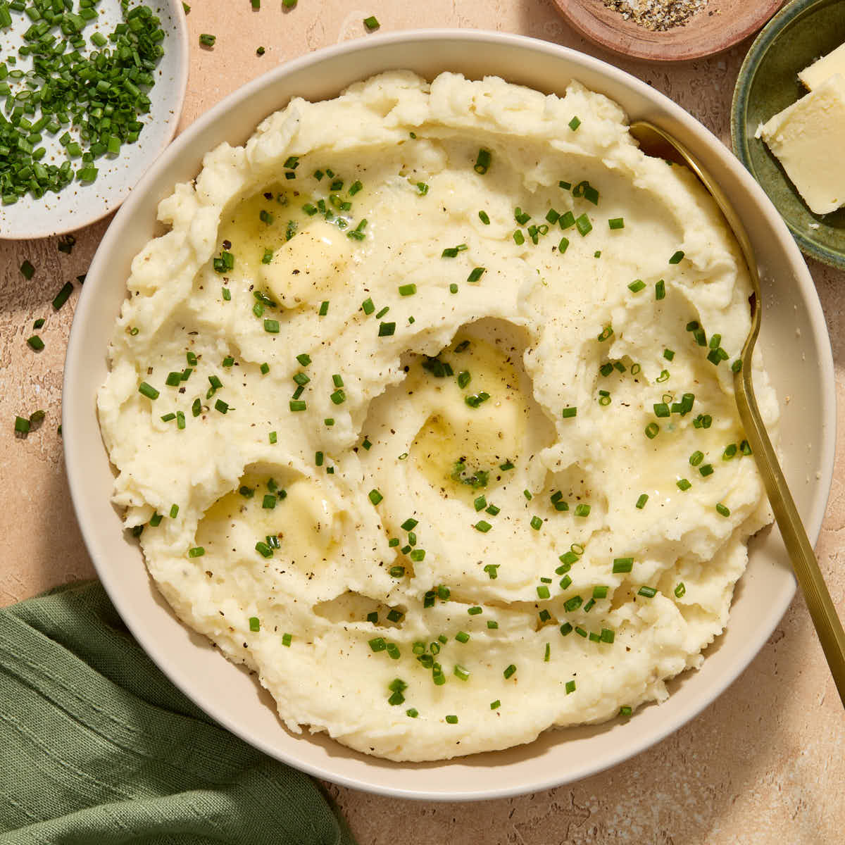 Air fryer mashed potatoes served in a bowl with chopped chives, butter and pepper on top.