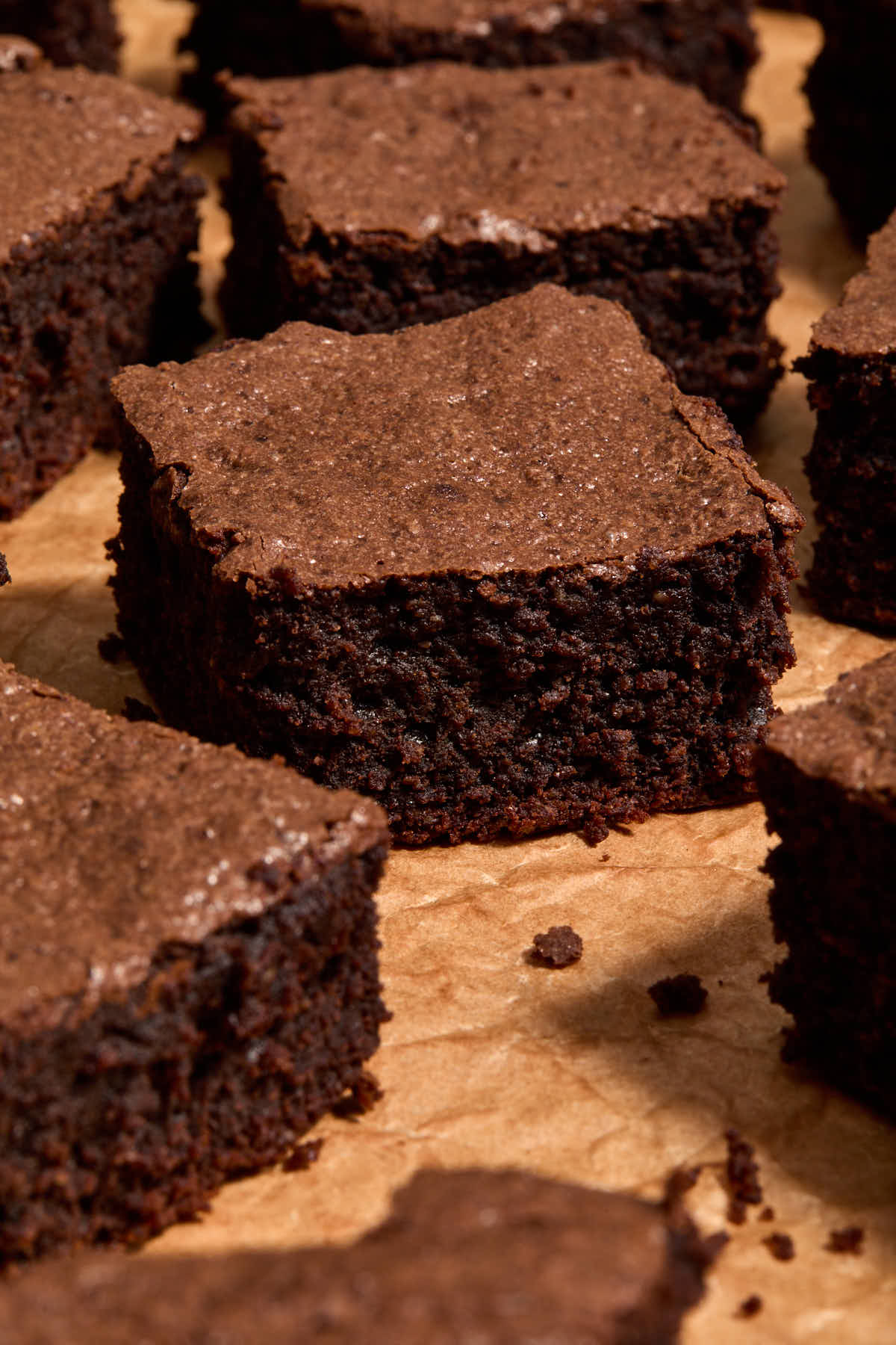 Brownies arranged on crumpled brown parchment paper.