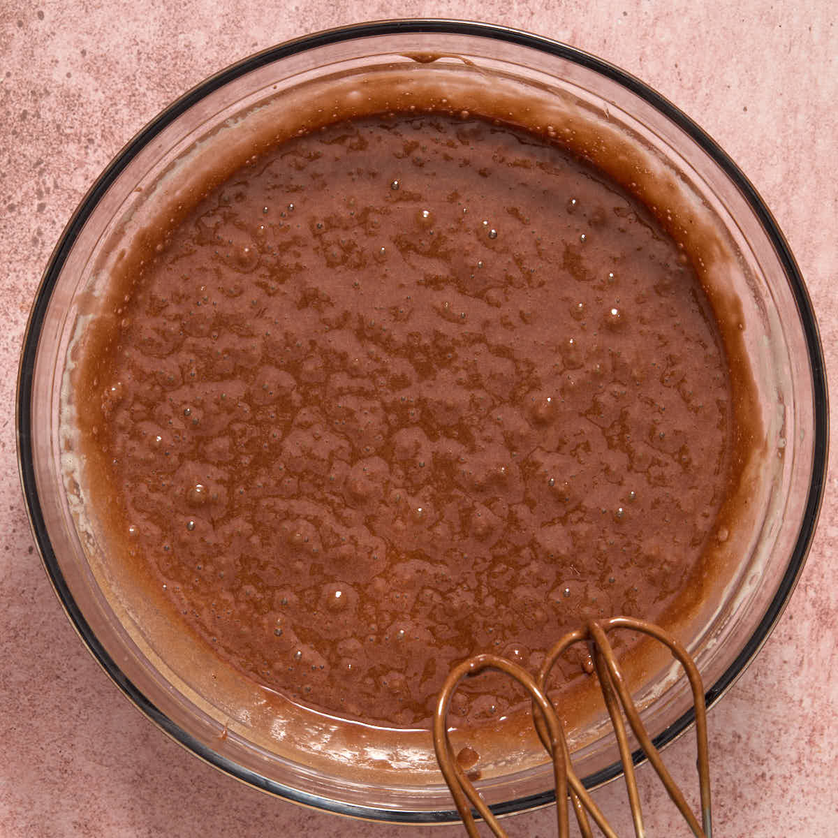 Melted chocolate mixed into the egg mixture in a glass bowl.