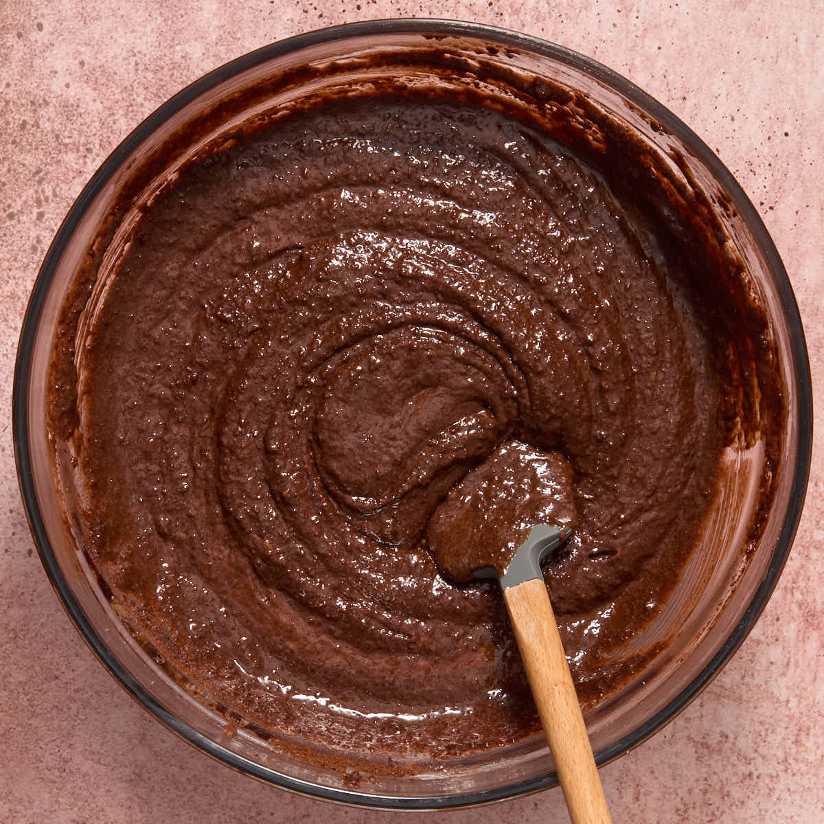 Brownie batter mixed together in a glass bowl with a spatula.