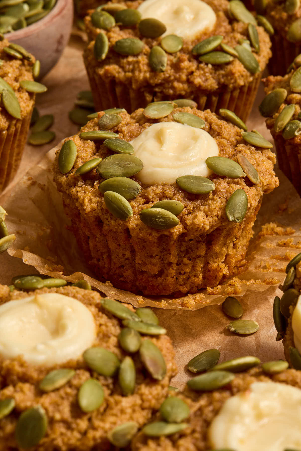 Pumpkin muffin on a parchment wrapper with other muffins surrounding it.