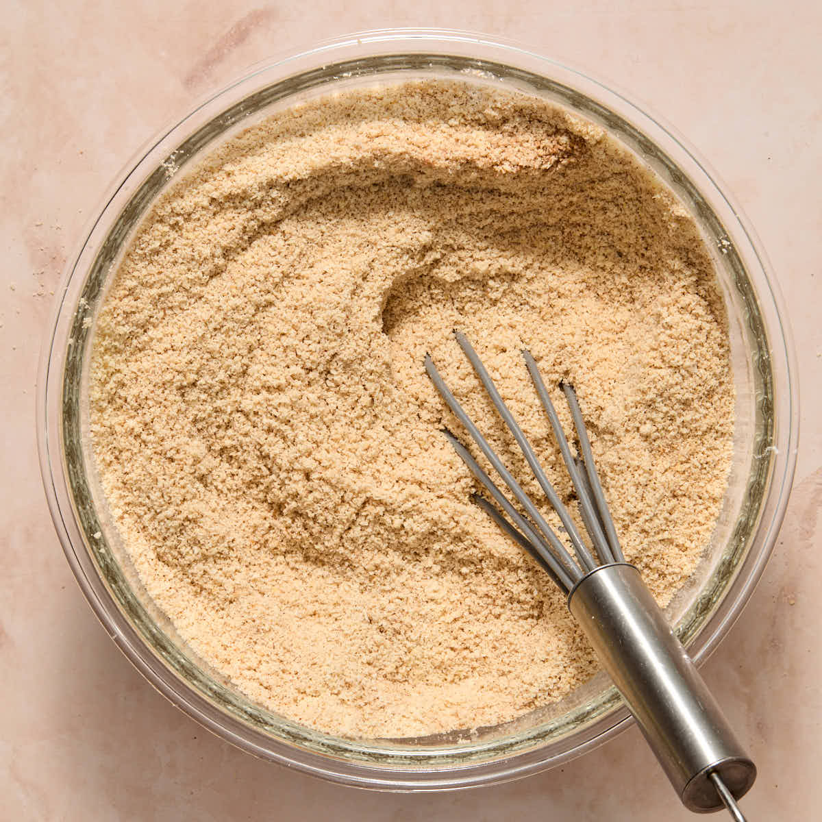 Almond flour and other dry ingredients whisked together in a glass bowl.