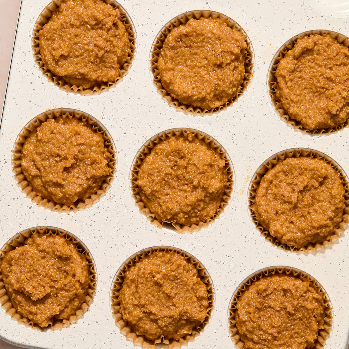 Pumpkin muffin batter portioned out into a muffin pan.