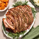Air fryer ham with savory, sugar-free glaze served on a white platter with fresh herbs.