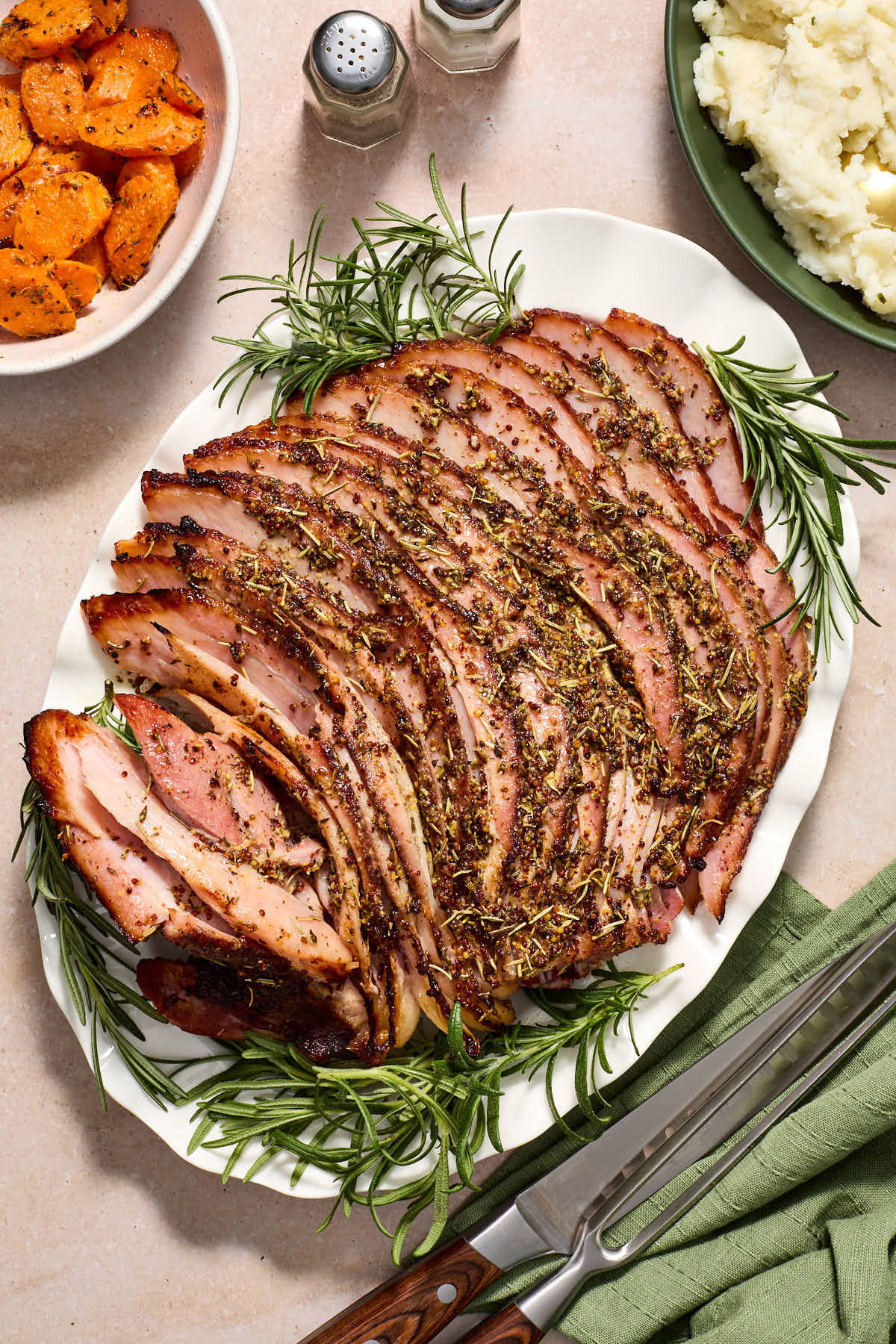 Air fried spiral ham served on a white platter with carrots and mashed potatoes on the side.