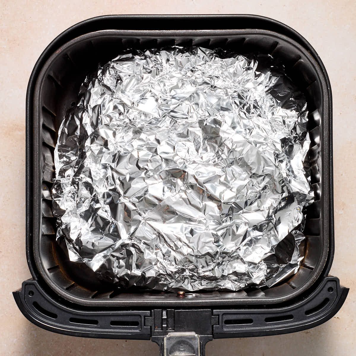 Ham wrapped in foil in the air fryer basket.
