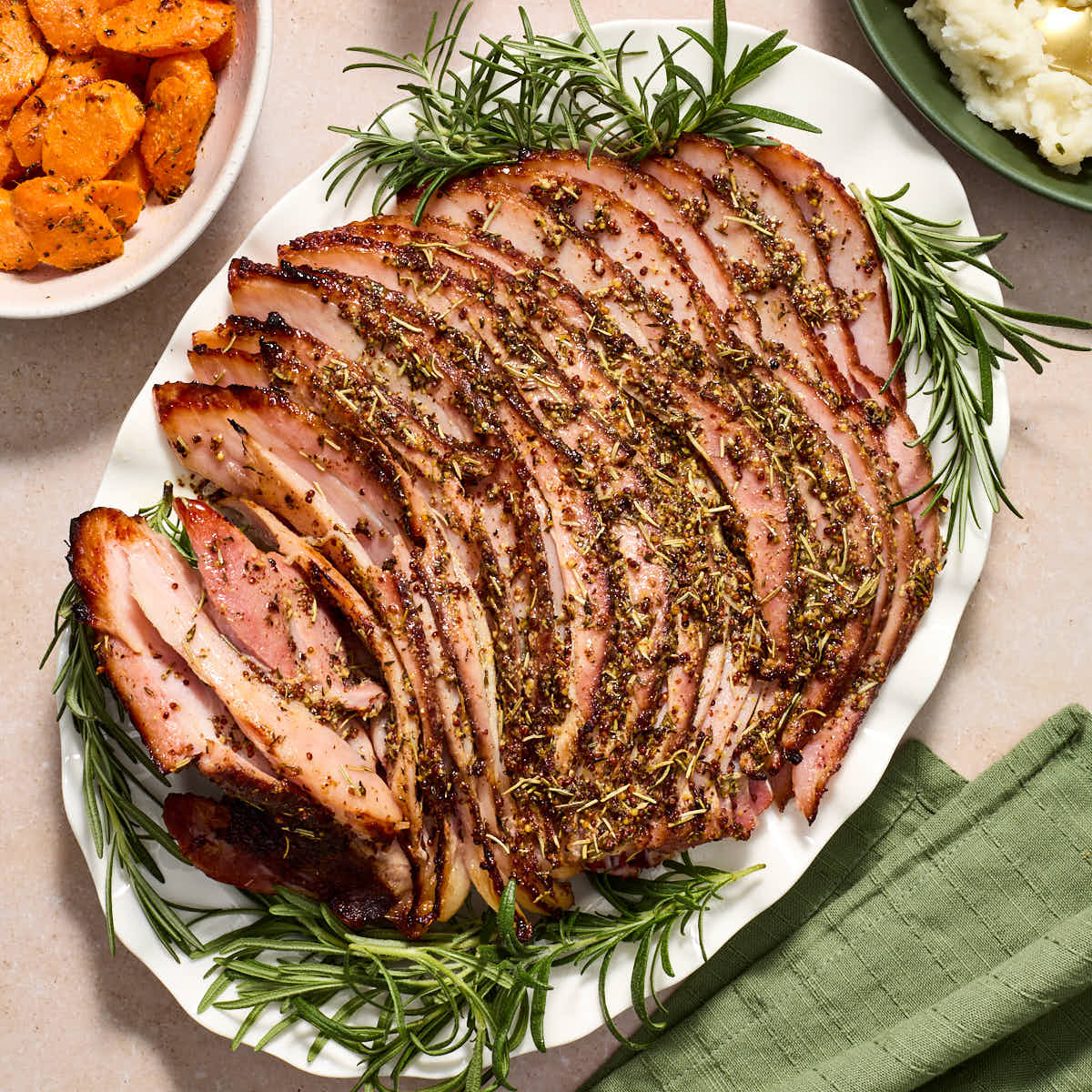 Air fryer ham with savory, sugar-free glaze served on a white platter with fresh herbs.
