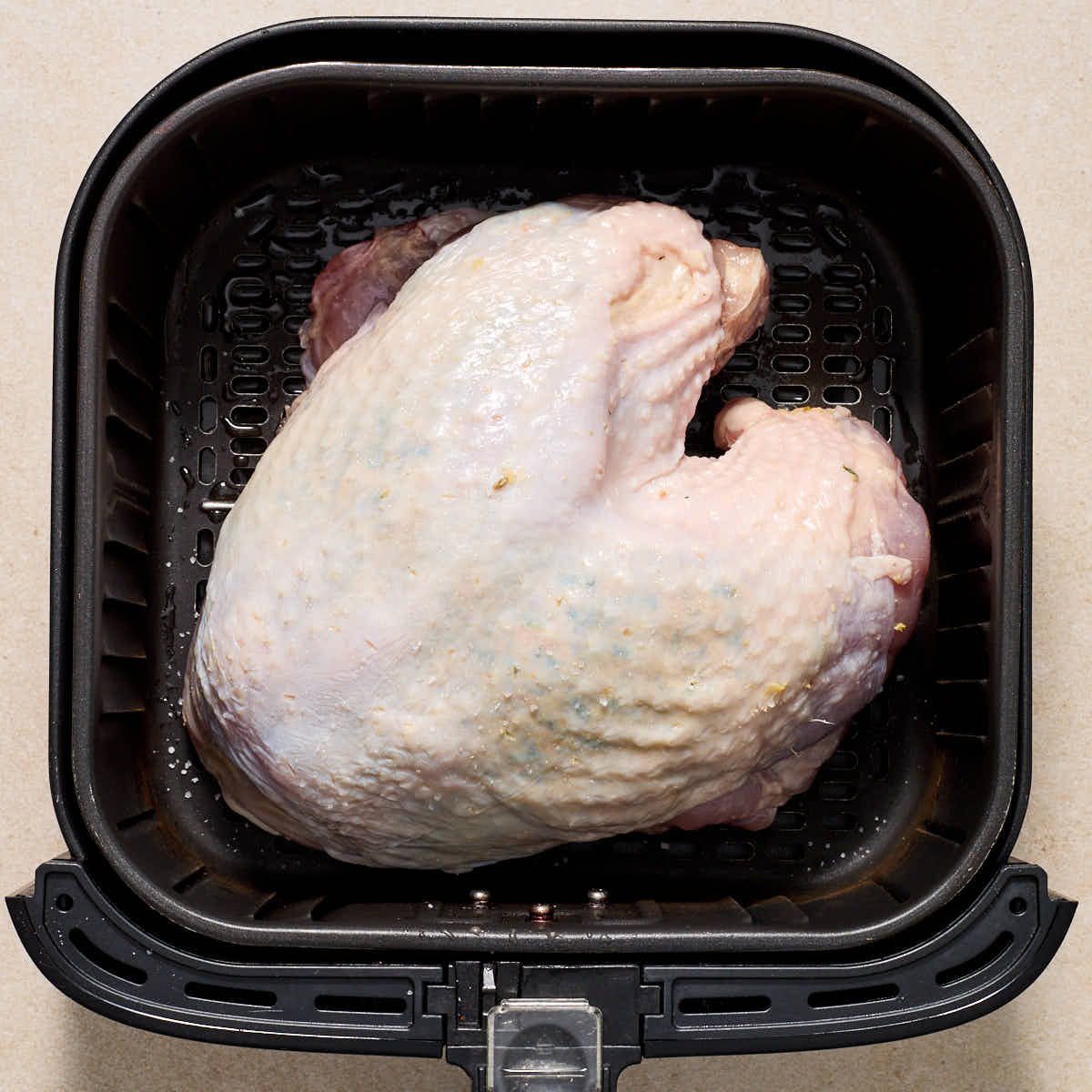 Raw turkey breast placed in the air fryer basket breast side up.